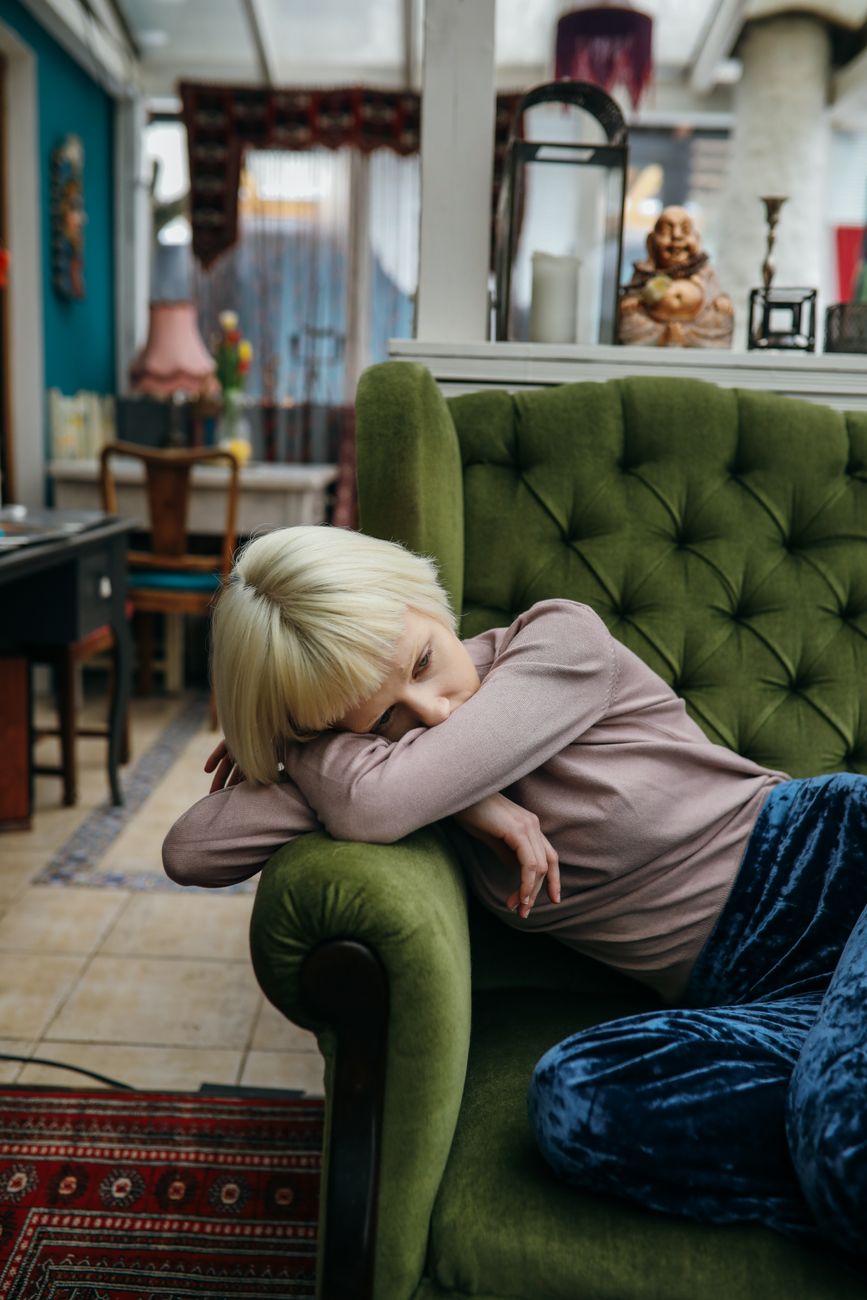 photo of a woman with blue pants sitting on a green sofa